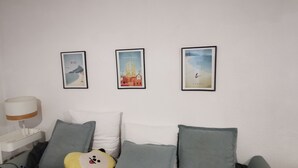 Una habitación con una cama, almohadas, una lámpara y tres cuadros colgados en la pared.