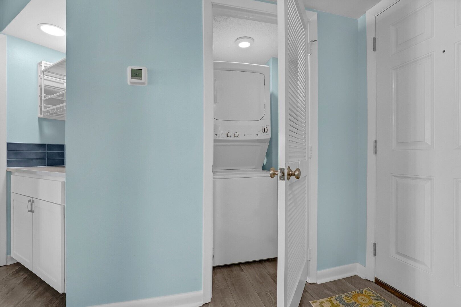 A room with light blue walls, a white door, and a visible laundry area with a washing machine.