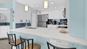 A modern kitchen with a central island, stainless steel appliances, and pendant lighting. - 2 Bedroom Oceanfront at St. Regis Resort (North Topsail Beach)