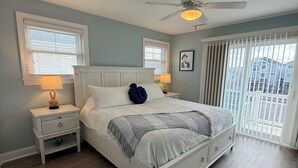 Een slaapkamer met een bed, twee nachtkastjes, een plafondventilator en een raam met zonwering.