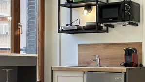 Une cuisine compacte équipée d’un four à micro-ondes encastré, d’un évier et d’un réfrigérateur.