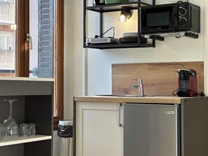 Eine kleine Küche mit Einbau-Mikrowelle, Spüle und Kühlschrank.