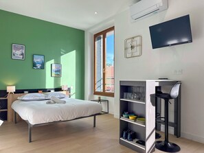 Ein modernes Hotelzimmer mit einem Bett, einem Schreibtisch, einem Bücherregal und einem Fernseher.