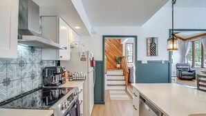A modern kitchen with a stove, oven, and dishwasher. There is a wooden staircase leading to a dining area with a view of the outdoors. - 1 Mi to Big Boulder Mountain: Townhome W/gas Grill (Lake Harmony)