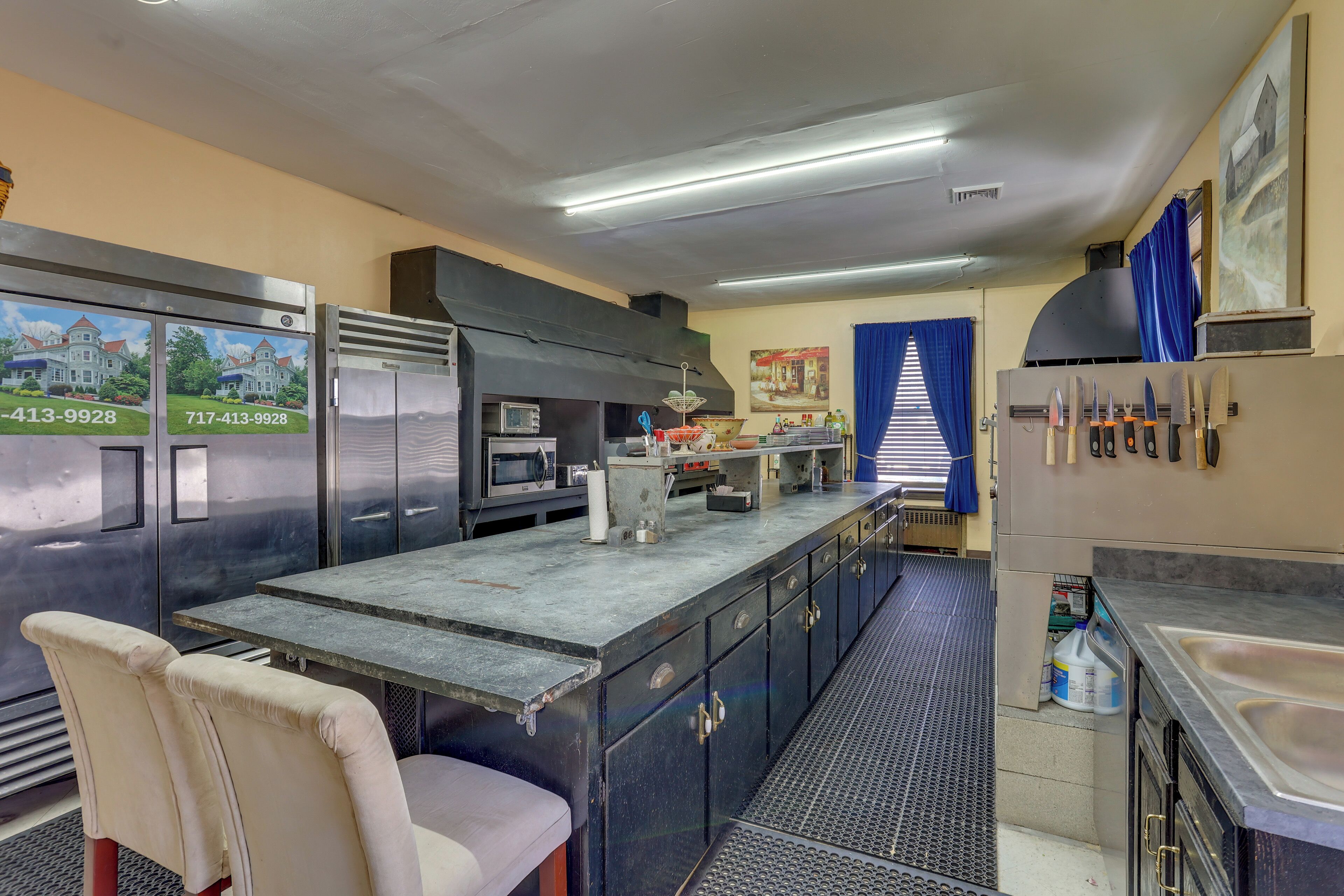 A commercial kitchen with stainless steel appliances, a long counter, and a chair.