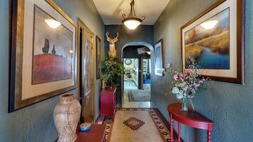 A hallway with framed artwork, a large vase, and a rug.