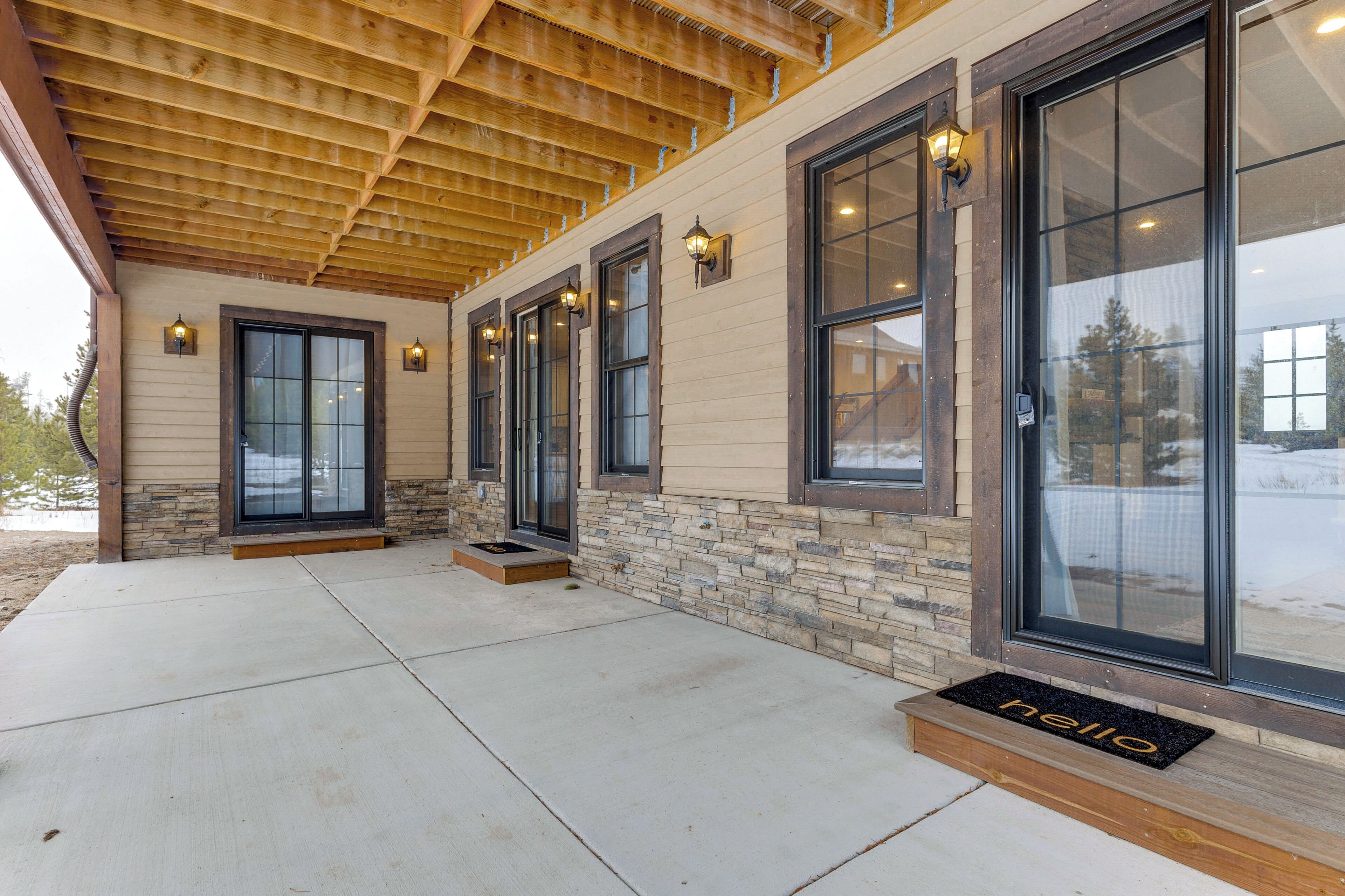 A building with a covered patio, large windows, and a welcome mat.