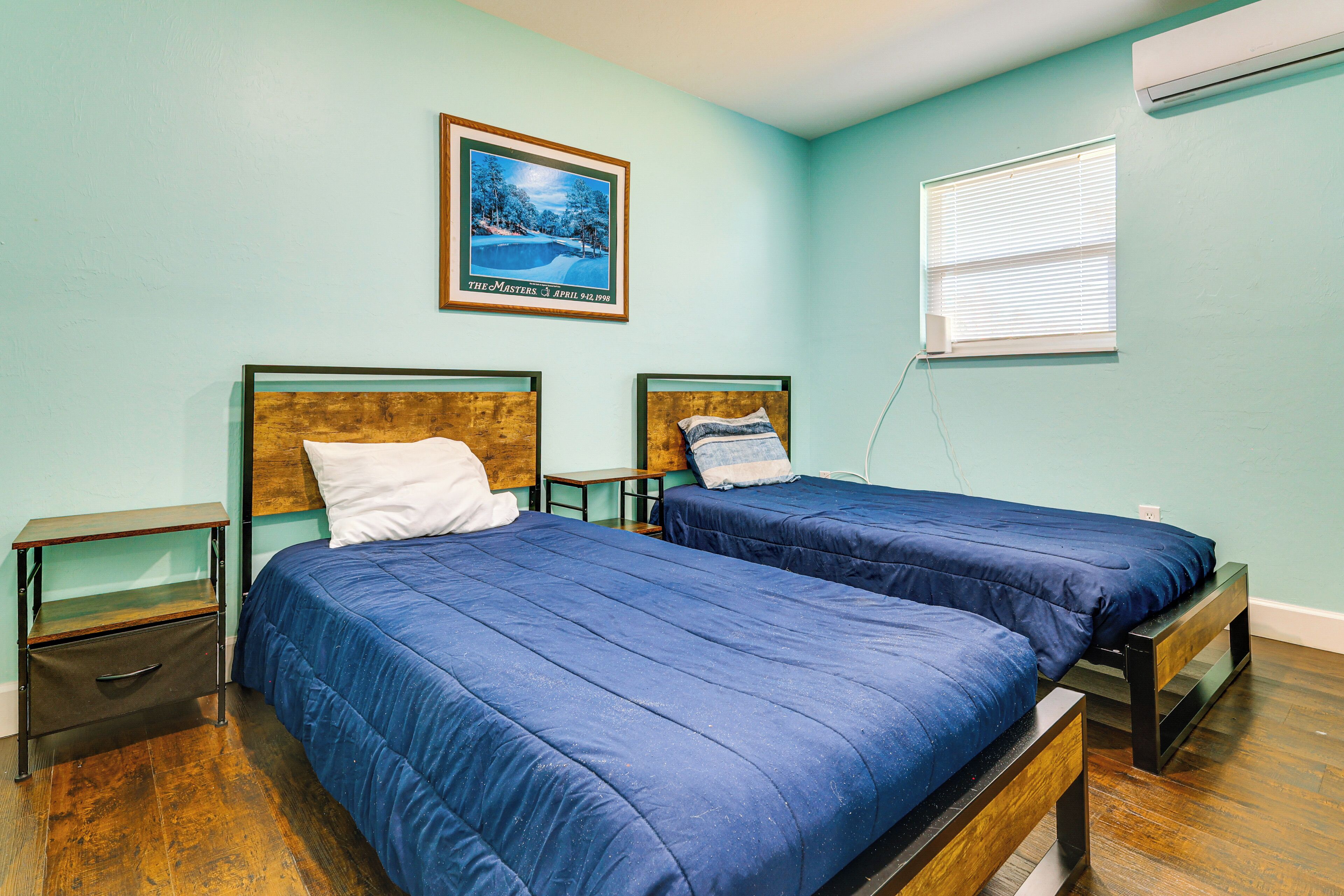 A bedroom with two beds, wooden headboards, and a picture on the wall.