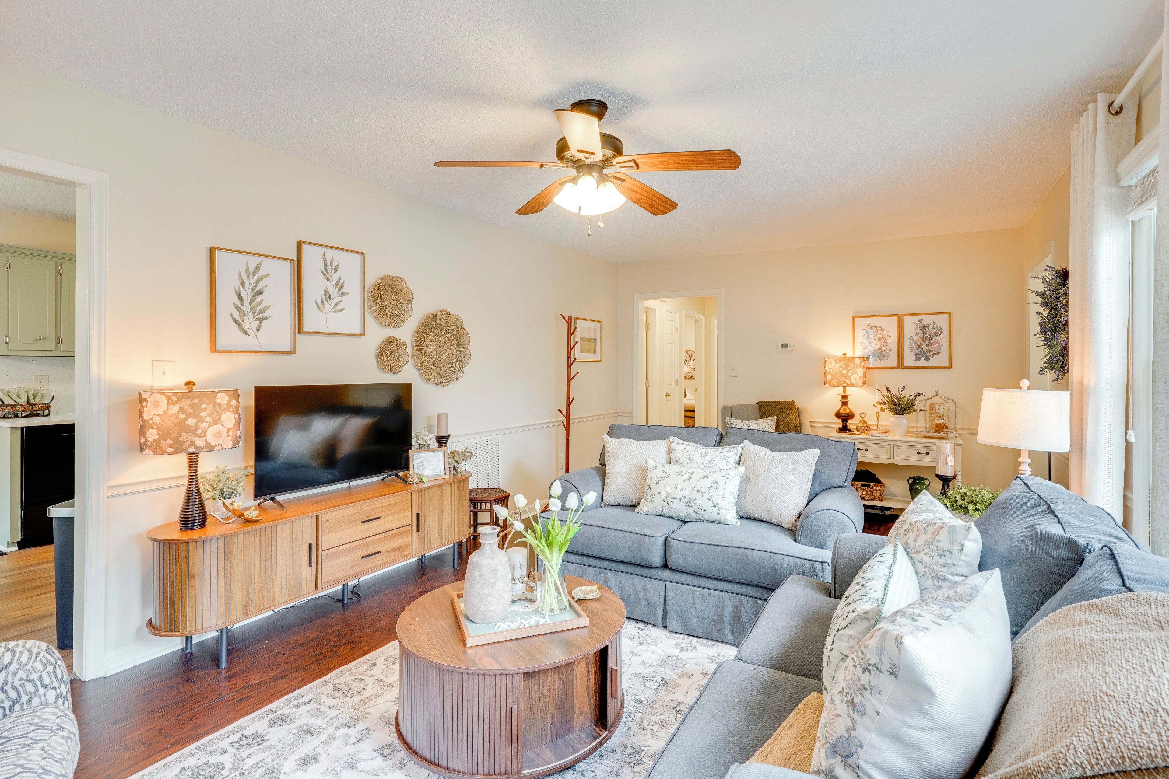 A living room with a TV, sofas, a coffee table, and a ceiling fan.