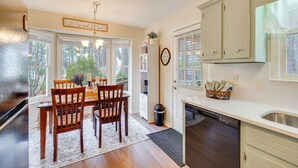 A kitchen with wooden chairs, a dining table, a dishwasher, and cabinets. - 'petals & Pillows Getaway' 1 Mi to Dtwn Wendell! (Wendell)