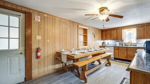 Ein Holzinnenraum mit einem Esszimmer für sechs Personen, einem Deckenventilator und Holzschränken.