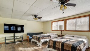 Ein Hotelzimmer mit zwei Betten, einem Deckenventilator, einem Flachbildfernseher und großen Fenstern mit Jalousien.