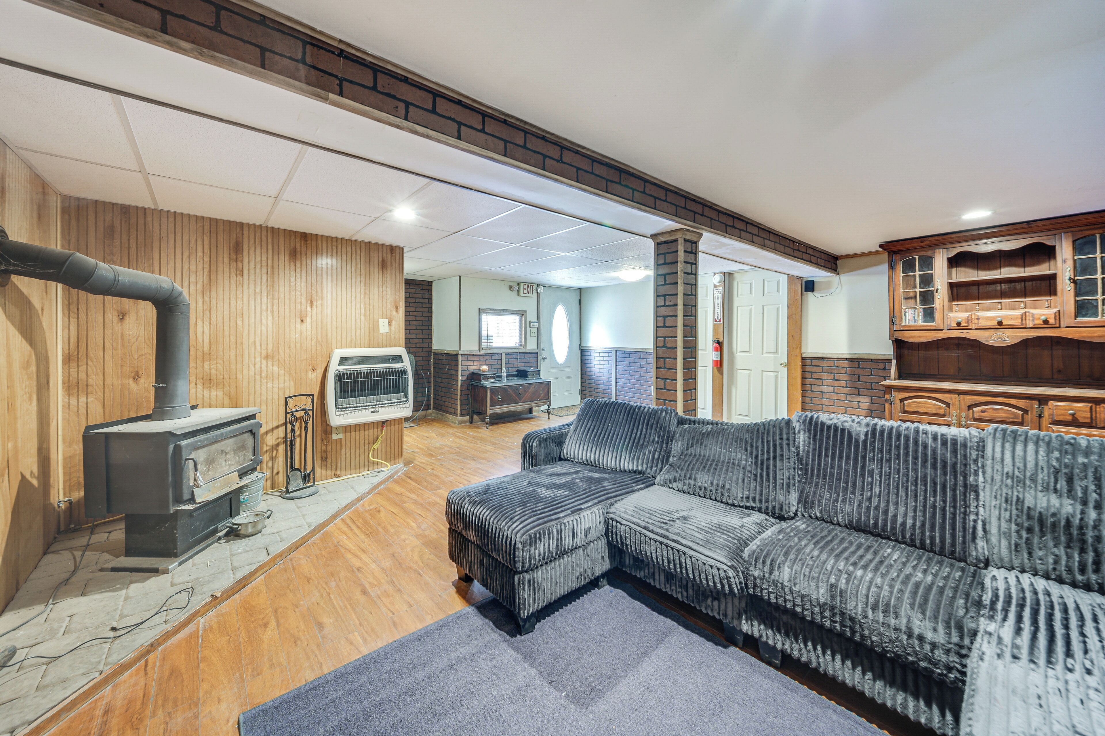 A cozy living room with a sectional sofa, a wood-burning stove, and a brick fireplace.
