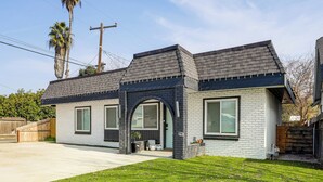 A two-story house with a brick facade, a dark roof, and a front entrance with a small porch. - Under 1 Mi to Med Center! Stylish Home in Tulare (Tulare)