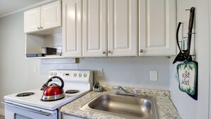 A kitchen with white cabinets, a stainless steel sink, a red kettle, and a wall-mounted bag rack. - Cozy Huntsville Studio Near Lowe Mill (Huntsville)