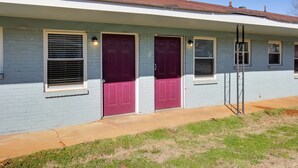 A single-story building with a light blue exterior, two red doors, and a small porch area. - Cozy Huntsville Studio Near Lowe Mill (Huntsville)