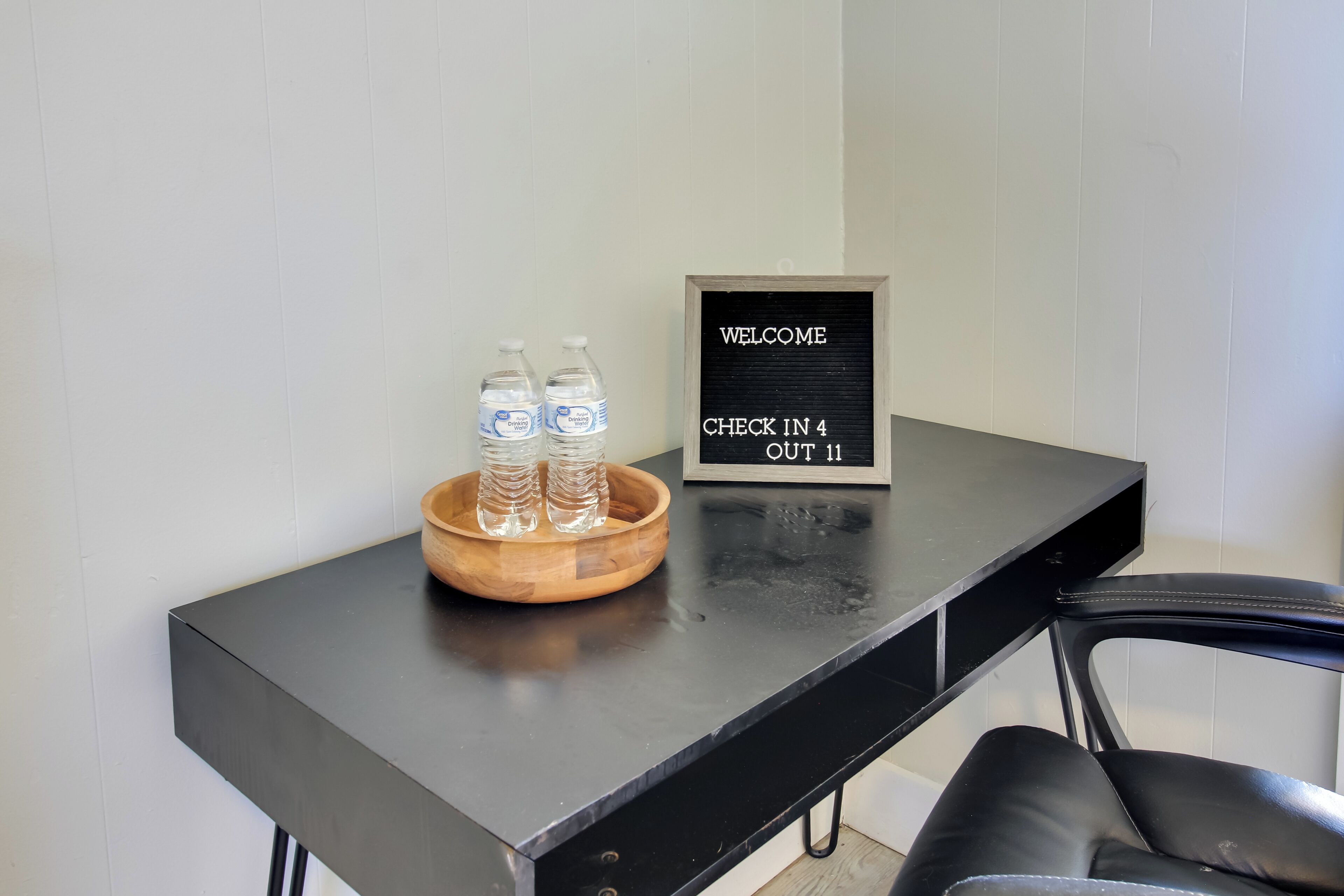 Un comptoir d’enregistrement avec un panneau d’accueil, deux bouteilles d’eau et un bol en bois.
