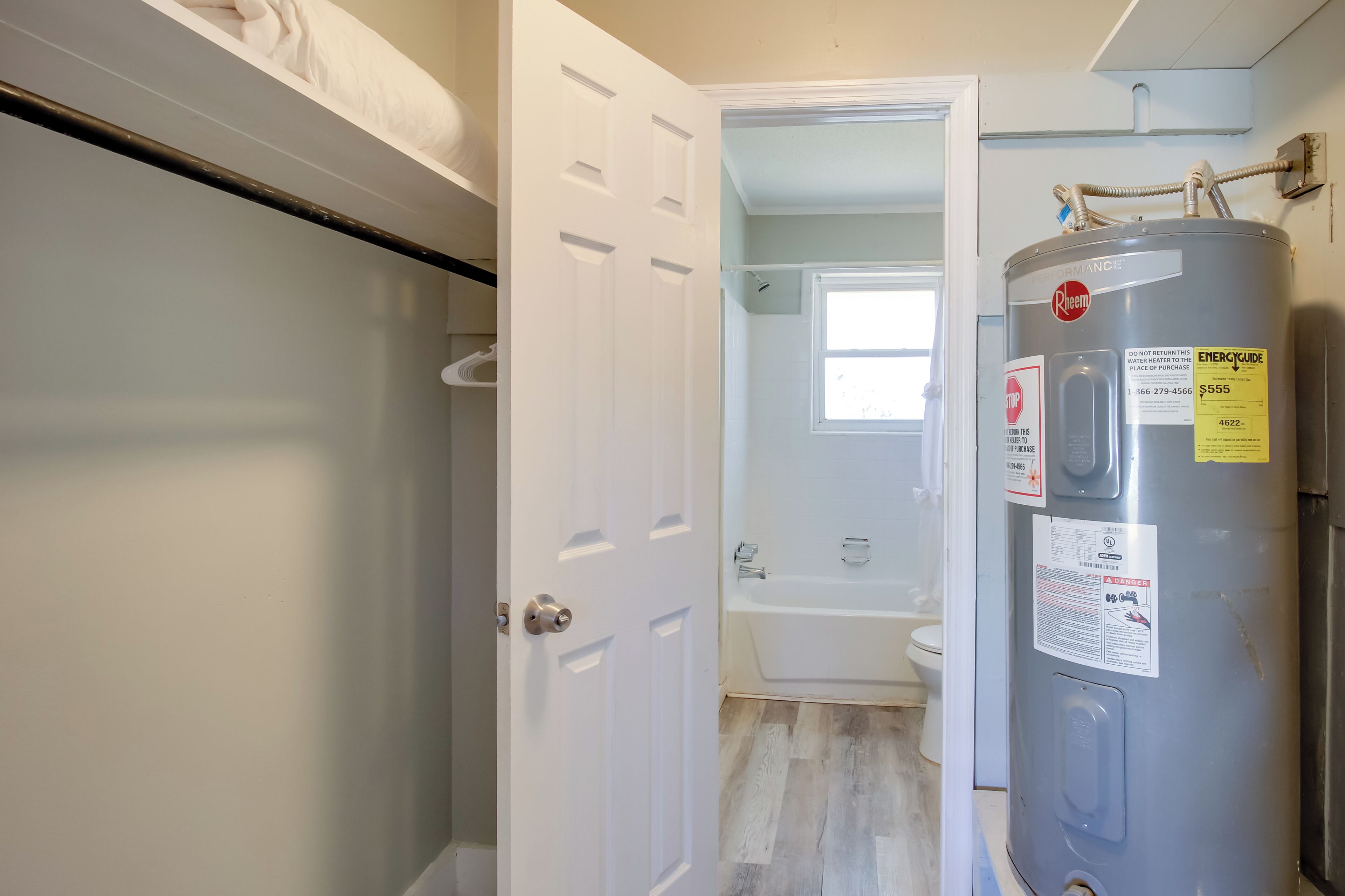 A bathroom with a white door, a bathtub, and a water heater.