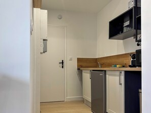 Une cuisine compacte avec une porte blanche, un lave-vaisselle encastré et un plan de travail en bois.