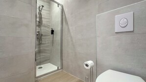 A modern bathroom with a glass-enclosed shower, a toilet, and a wall-mounted toilet paper holder. - #IH - Le Victoria 4 💟 (Grenoble)