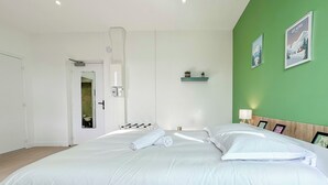 Una camera da letto moderna con un letto grande, una parete verde a contrasto e un piccolo ripiano con piante.
