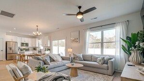 A modern living room with a sofa, chairs, a coffee table, and a view of the kitchen. - 4 Mi to Surf City Beaches! Family Coastal Retreat (Hampstead)