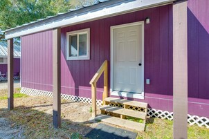 A single-story building with a purple exterior, a white door, and a small window with shutters.