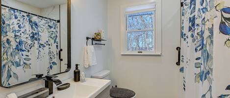 A bathroom with a white sink, a mirror with a floral pattern, a toilet, and a shower curtain with a floral pattern.