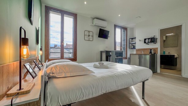 Une chambre d’hôtel moderne équipée d’un lit, d’une table de chevet et d’un espace bureau.