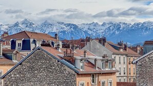 Une ville aux bâtiments en pierre, avec une chaîne de montagnes en arrière-plan.