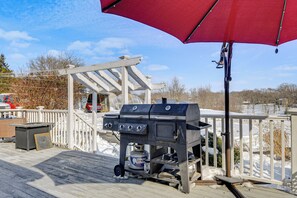 Ein Grill mit Holzboden und ein roter Sonnenschirm darüber.