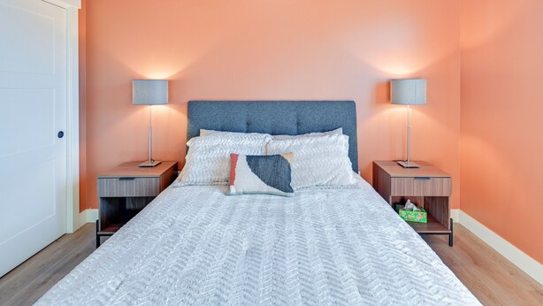 Une chambre à coucher comprenant un lit, deux tables de chevet et deux lampes fixées au mur.