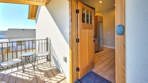 Un balcon doté d’un plafond en bois, une porte donnant sur une cuisine et une vue sur un bâtiment en arrière-plan.