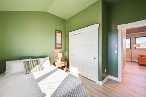 Une chambre  à coucher comprenant un lit, une table de chevet, une lampe et une porte donnant sur une autre pièce.
