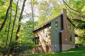 Una casa de madera con base de piedra, rodeada de un bosque.