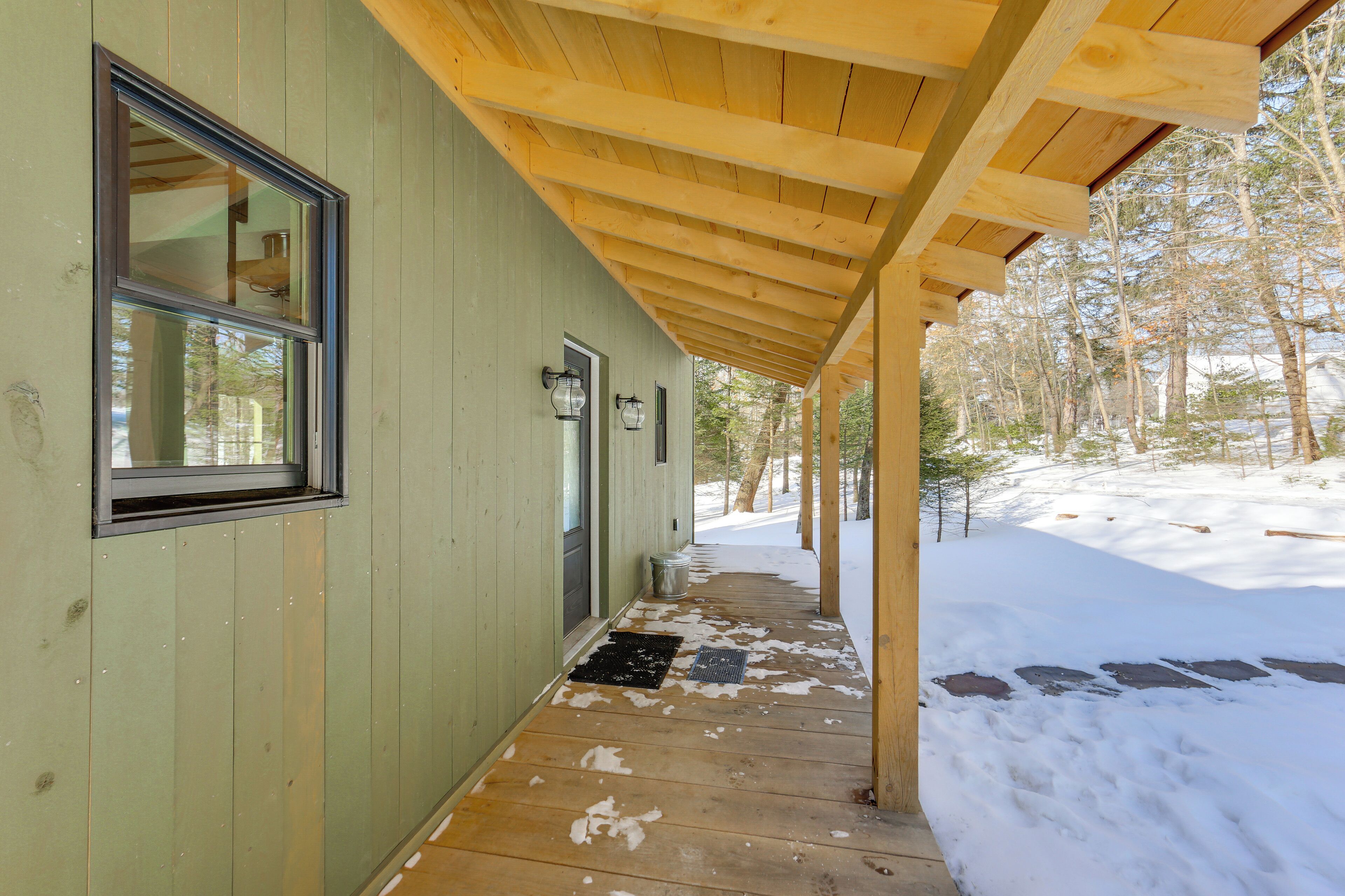 Un porche de madera con pared exterior verde, una ventana y una puerta.