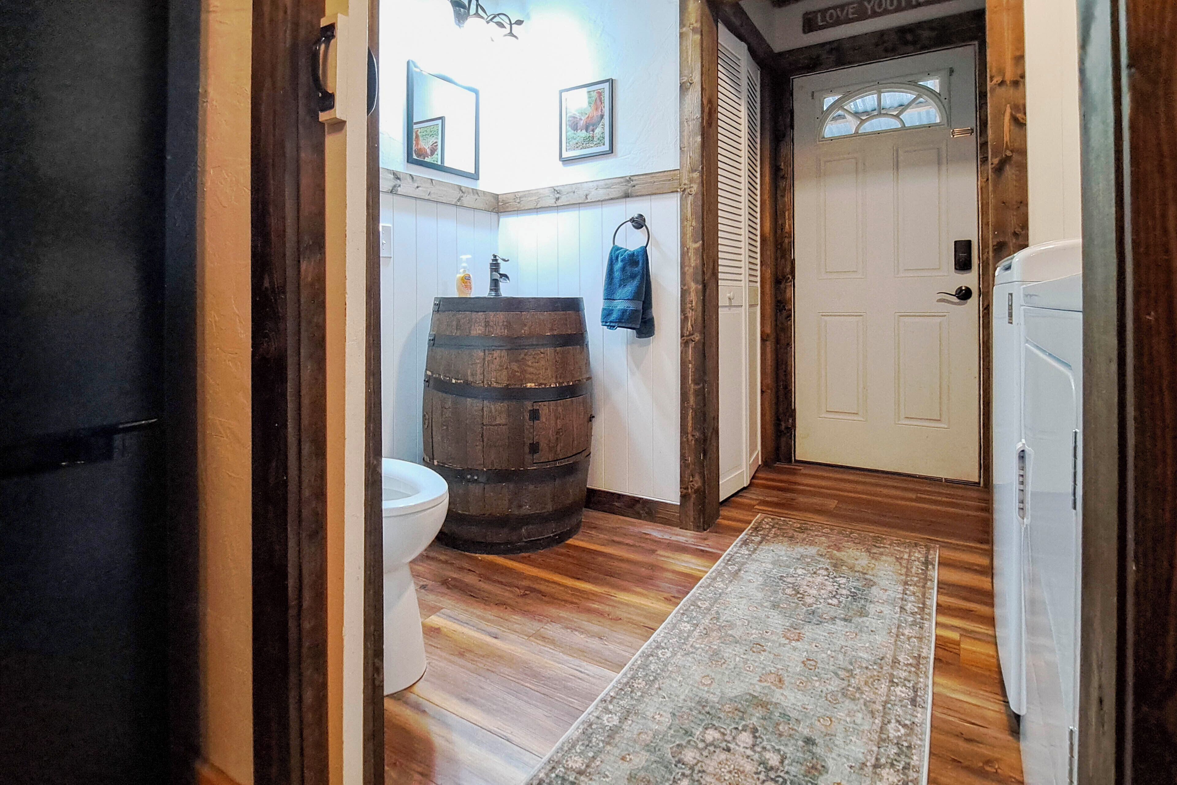 A bathroom with a wooden barrel, toilet, and a white door.