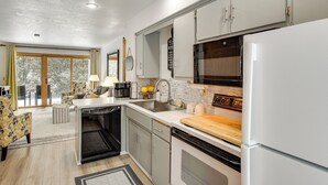 Una cocina moderna con armarios blancos, una encimera de madera y un horno empotrado.