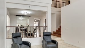 A spacious living area with two black leather recliners, a staircase, and a view into the dining area. - Private Pool, Fire Pit & Grills: Las Vegas Getaway (Las Vegas)