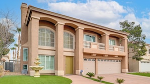 A two-story house with a balcony, large windows, and a well-maintained lawn. - Private Pool, Fire Pit & Grills: Las Vegas Getaway (Las Vegas)