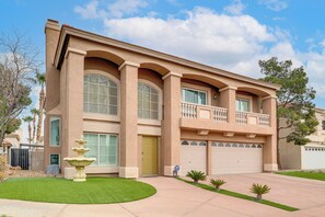 A two-story house with a balcony, large windows, and a well-maintained lawn.