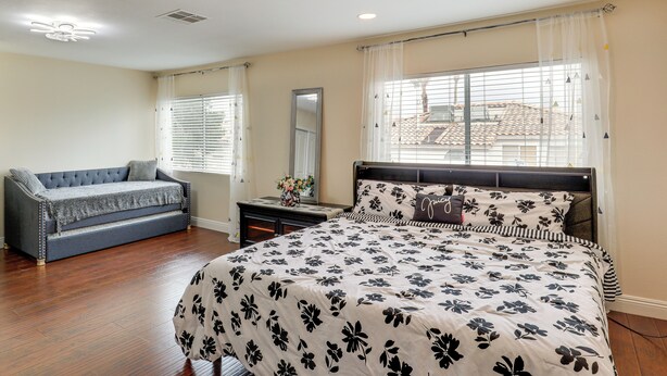 A bedroom with a large bed, a sofa, a dresser, and a window with blinds. - Private Pool, Fire Pit & Grills: Las Vegas Getaway (Las Vegas)