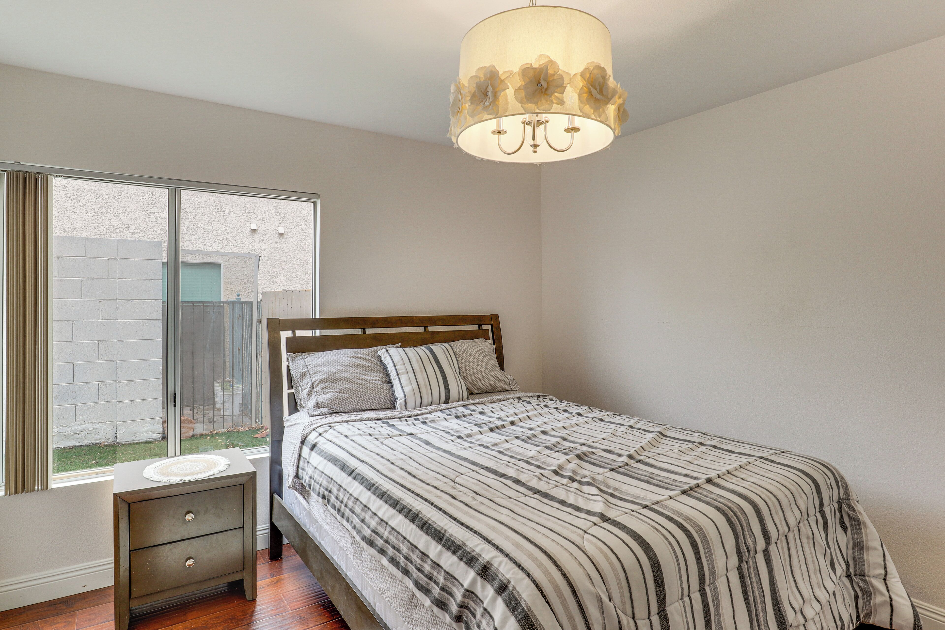 Une chambre à coucher avec un lit, une table de chevet, une fenêtre et un luminaire au plafond.