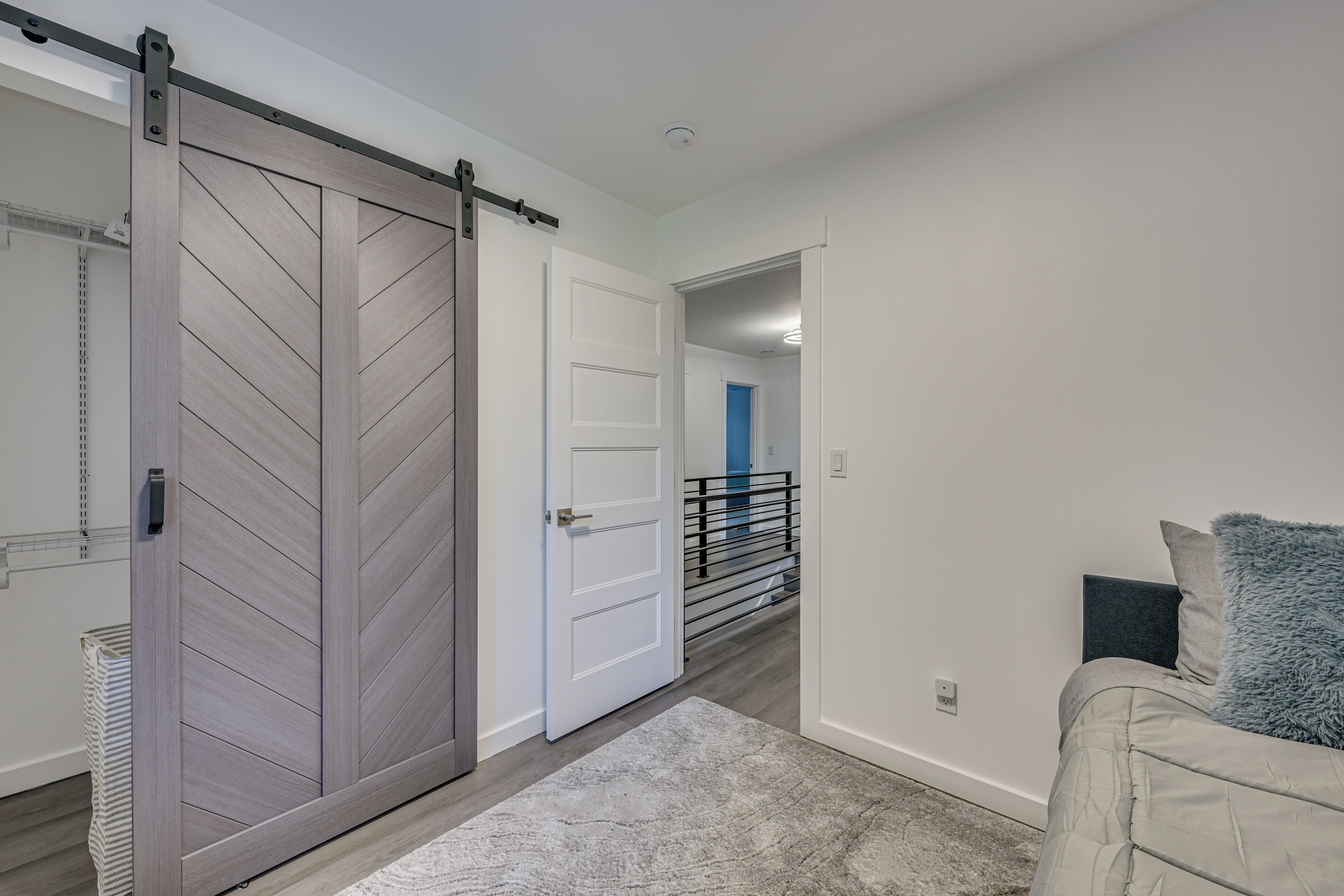 A modern interior with a sliding door, a staircase, and a bed with pillows.