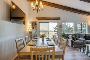 A dining area with a wooden table set for four, flanked by wooden chairs, a chandelier, and a large window offering a view of the outdoors. - Modern Heavenly Ski Resort Mountain-top Retreat (Stateline)