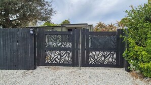 A gated entrance with decorative panels and a gravel driveway. - Riverfront Oasis: Fish, Grill & Chill in Stuart! (Stuart)