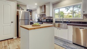 A modern kitchen with white cabinets, stainless steel appliances, and a large window providing natural light. - Riverfront Oasis: Fish, Grill & Chill in Stuart! (Stuart)