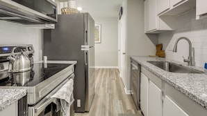 A modern kitchen with stainless steel appliances, a granite countertop, and a wooden floor. - 1 Mi to Tiger Stadium: Sleek University South Gem! (Baton Rouge)