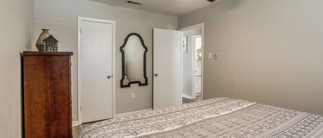 A bedroom with a bed, a ceiling fan, a dresser, and a mirror.