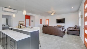 Amplia sala de estar con isla de cocina, sofá de cuero marrón y ventilador de techo.